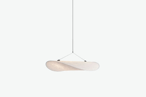 Wisząca lampa z jasnym owalnym kloszem podwieszonym na cienkich linkach.