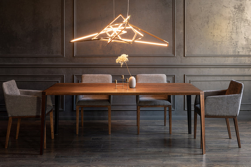 Drewniany stół z krzesłami w ciemnej jadalni pod geometryczną lampą wiszącą.