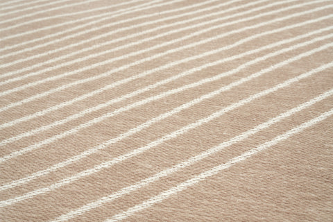 Zbliżenie beżowego dywanu z białymi falistymi liniami.