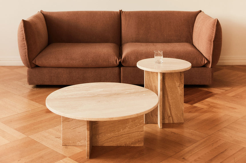 Brązowa sofa oraz dwa okrągłe stoliki.