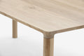 Zbliżenie na blat i narożnik drewnianego stołu.